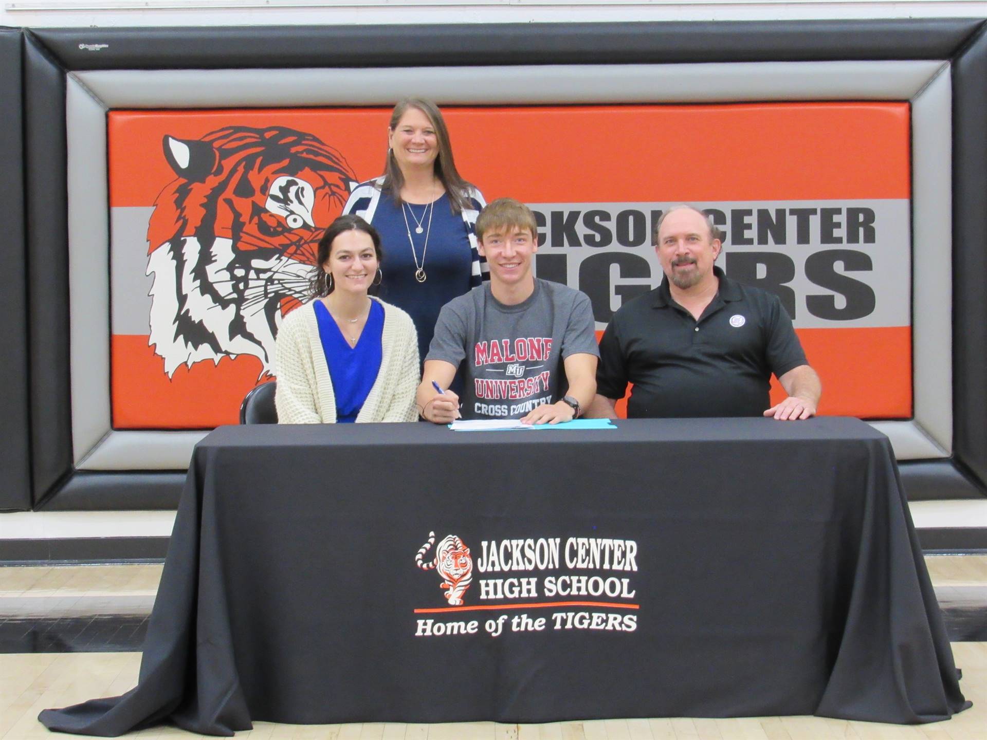 Cross country runner and coaches at college signeing