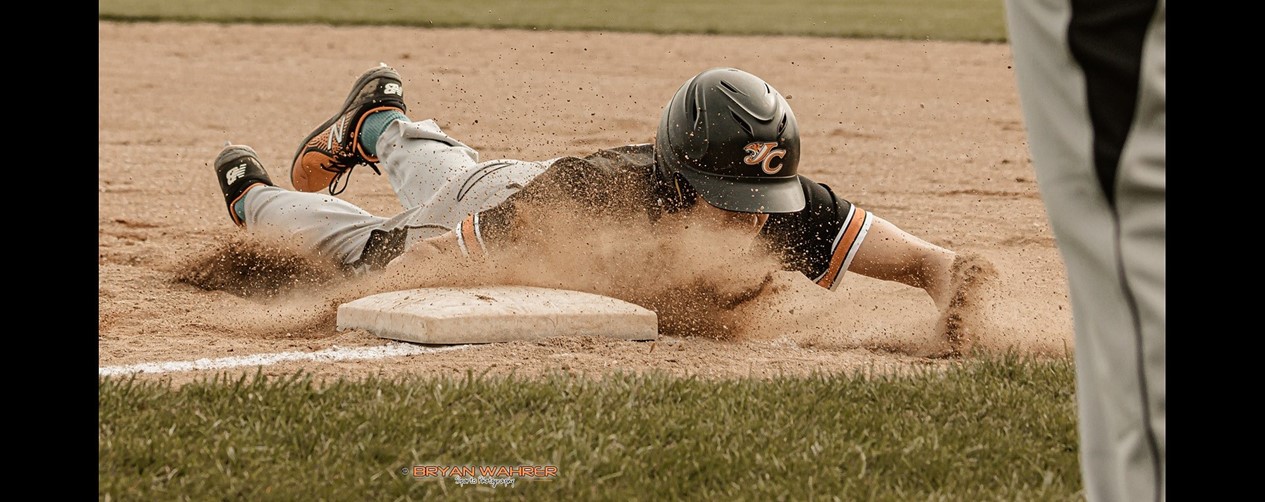 high school boys baseball player sliding into base